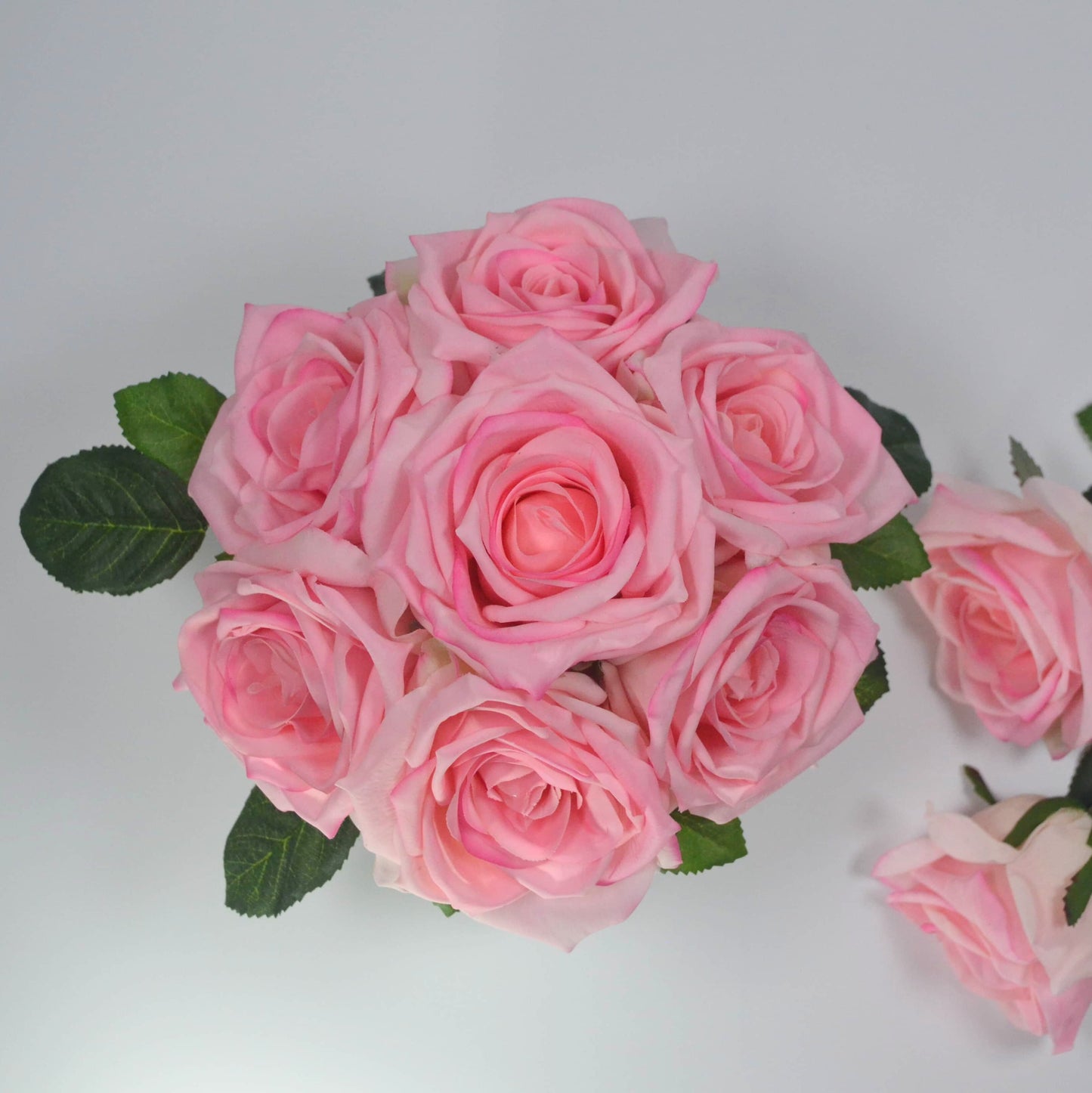 Bouquet of pink roses with green leaves on a light gray background