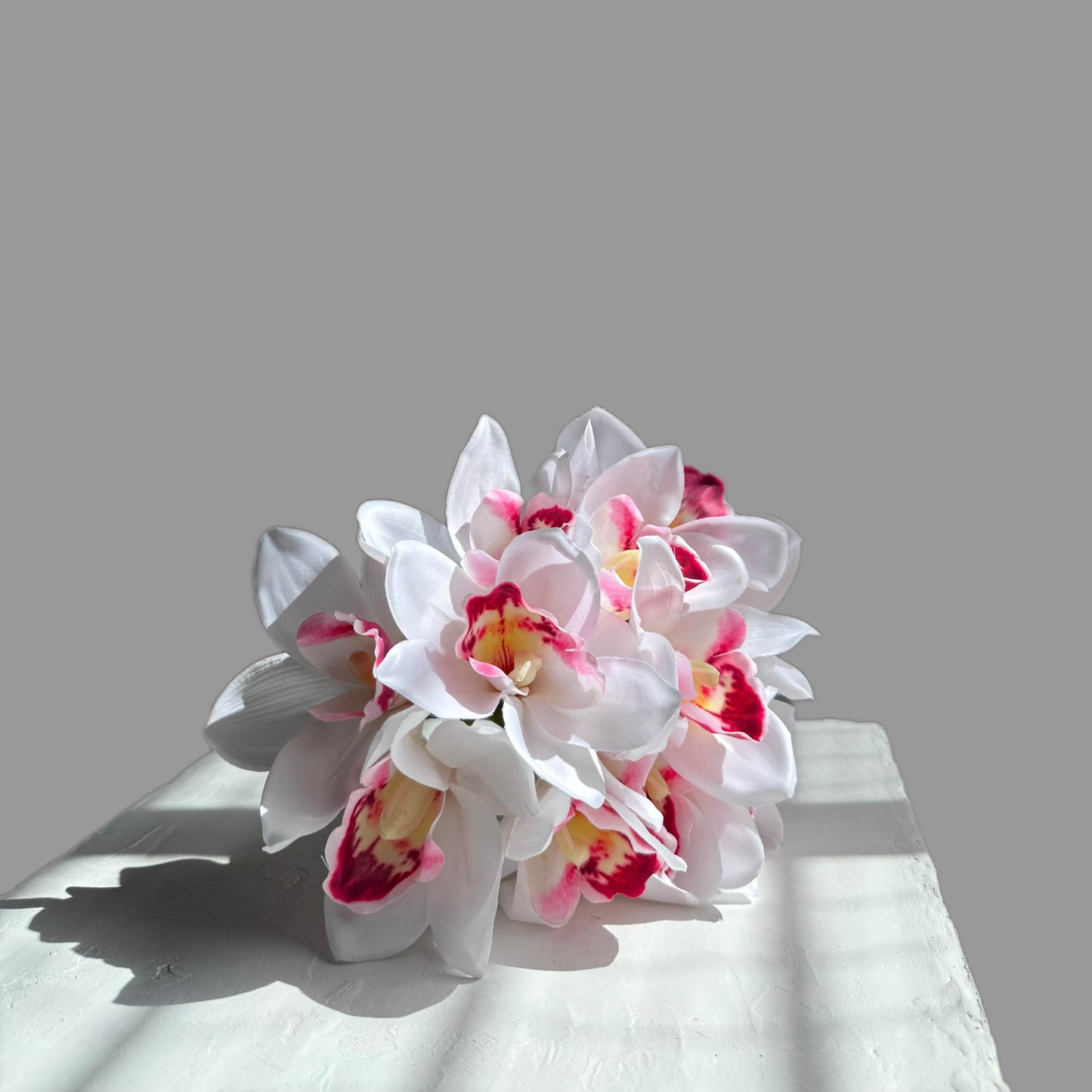 Bouquet of white and pink flowers on a light gray surface with a neutral background