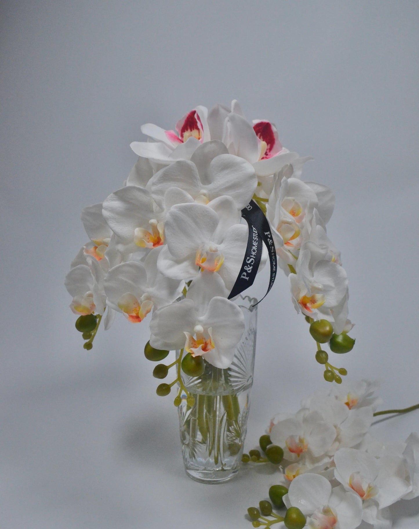 White orchid bouquet with a clear vase on a gray background