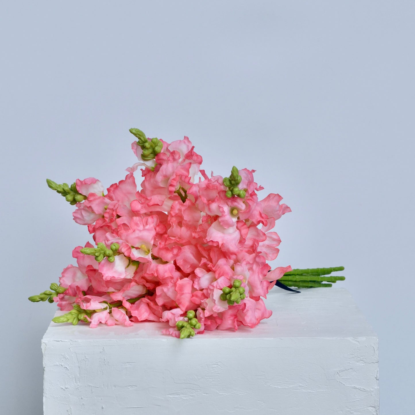 Pink flowers on a white cake against a light gray background