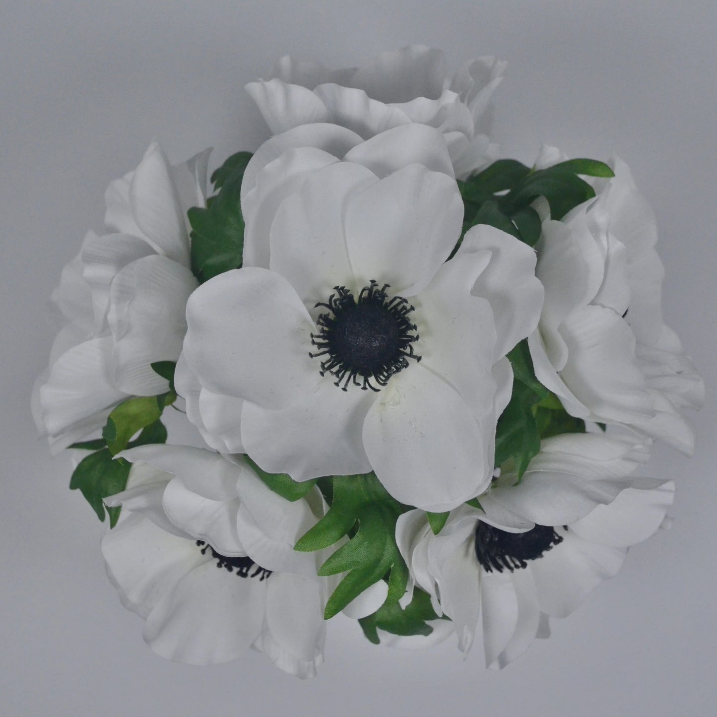 Bouquet of white flowers with green leaves on a gray background