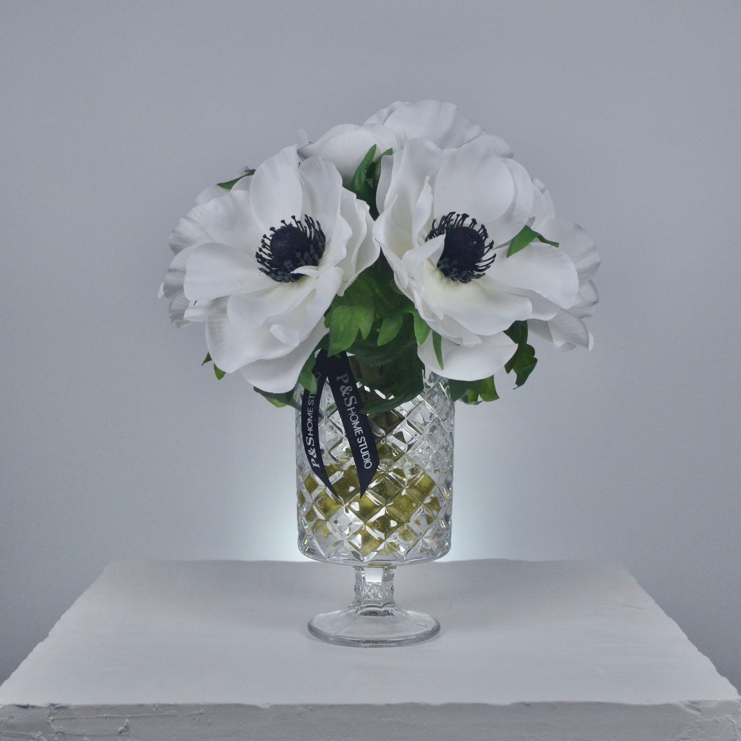 Clear glass vase with white flowers and a black ribbon on a gray background