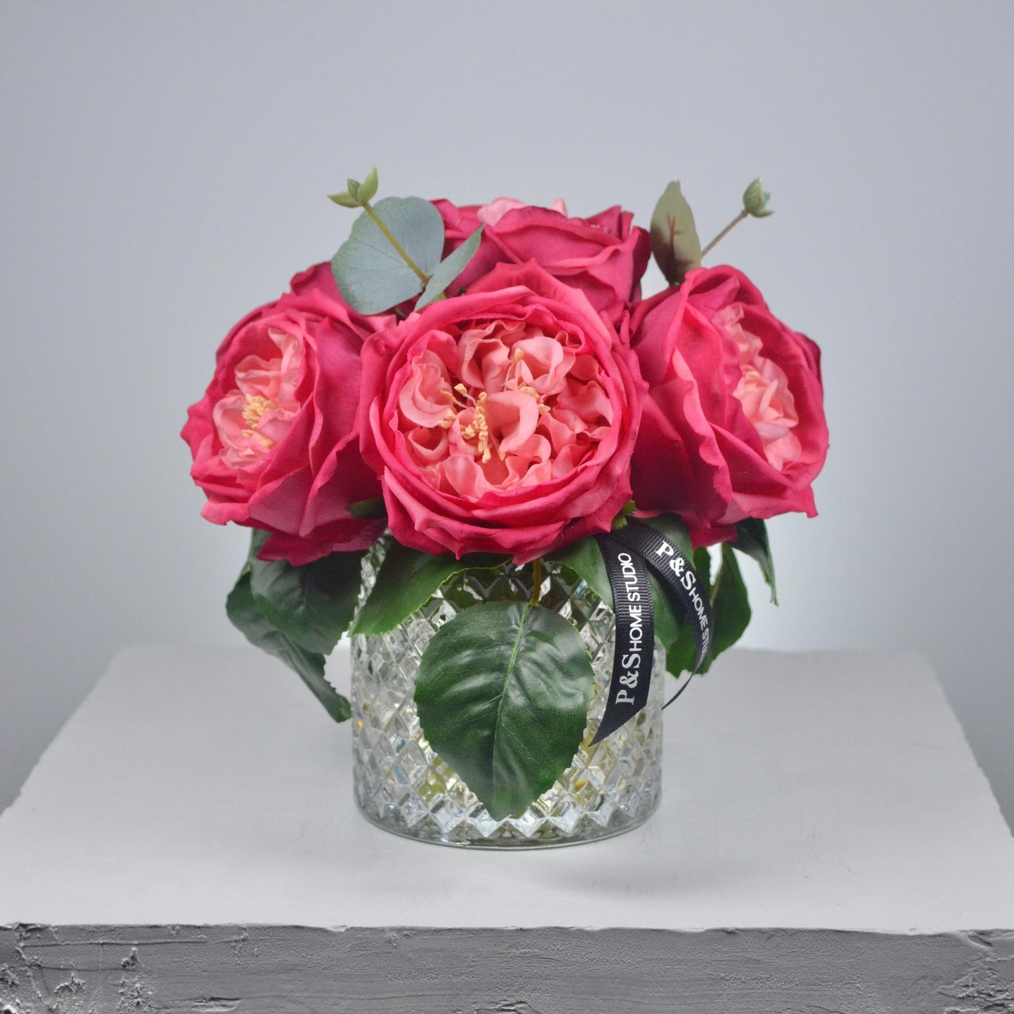 Bouquet of pink roses in a clear glass vase on a light gray background