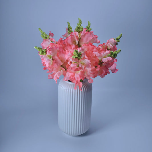 White vase with pink flowers on a light blue background