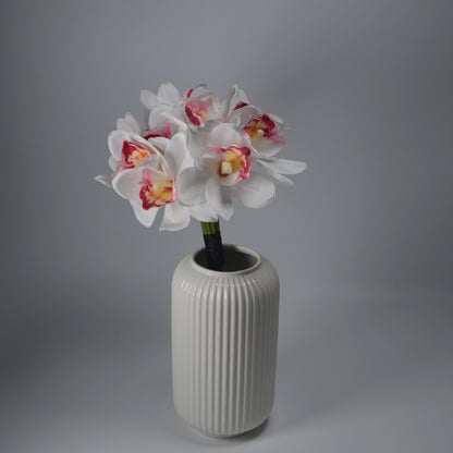 White ribbed vase with artificial flowers on a gray background