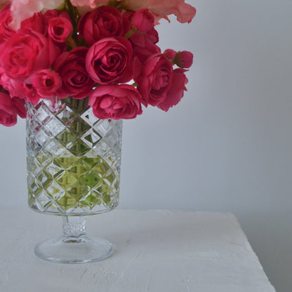 Clear glass vase with pink flowers on a white surface