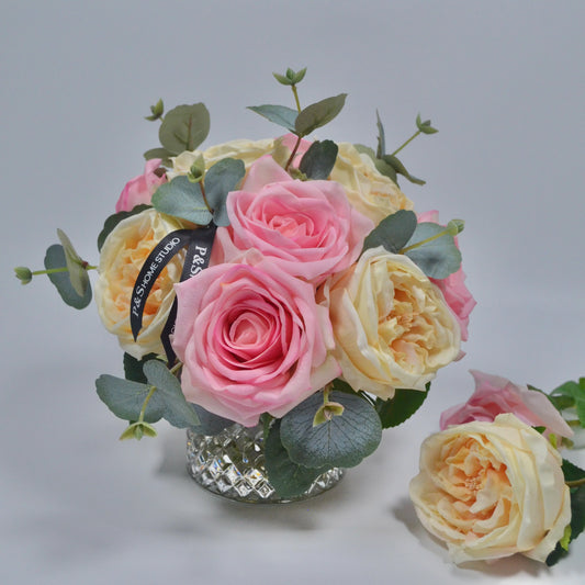 Bouquet of pink and yellow roses with green leaves on a gray background