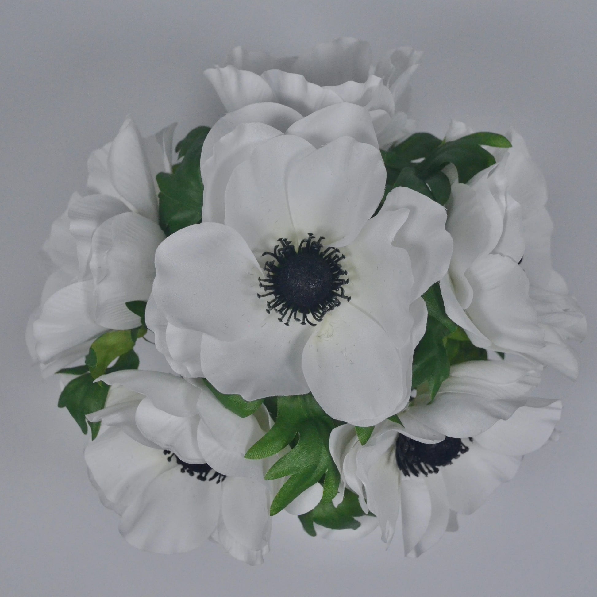 Bouquet of white flowers with green leaves on a gray background