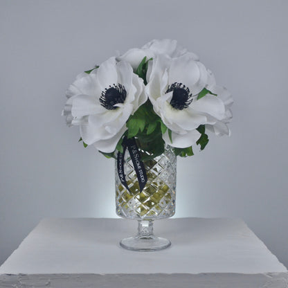Clear glass vase with white flowers and a black ribbon on a gray background