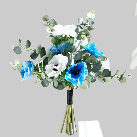Bouquet of blue and white flowers with green leaves on a gray background